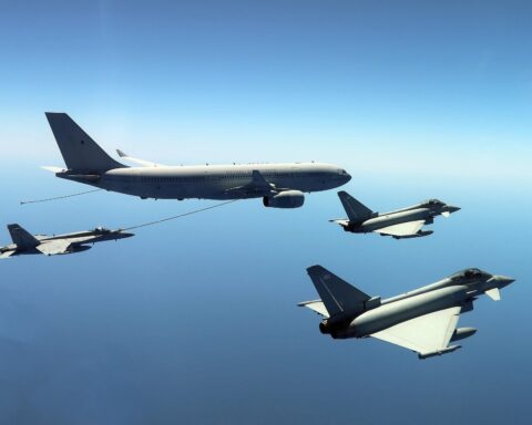 RAF Voyager A330 MRTT tanker with refuelling hose deployed, refuelling a fighter jet with two RAF Typhoons in formation