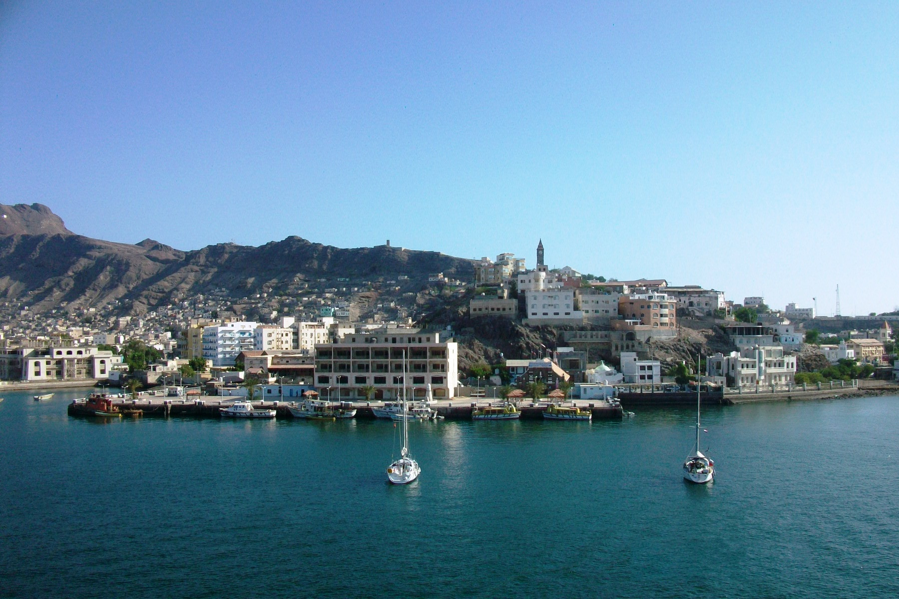 Aden harbour seen from the water, with the volcanic Tawahi headland rising behind the waterfront buildings and coast guard jetties