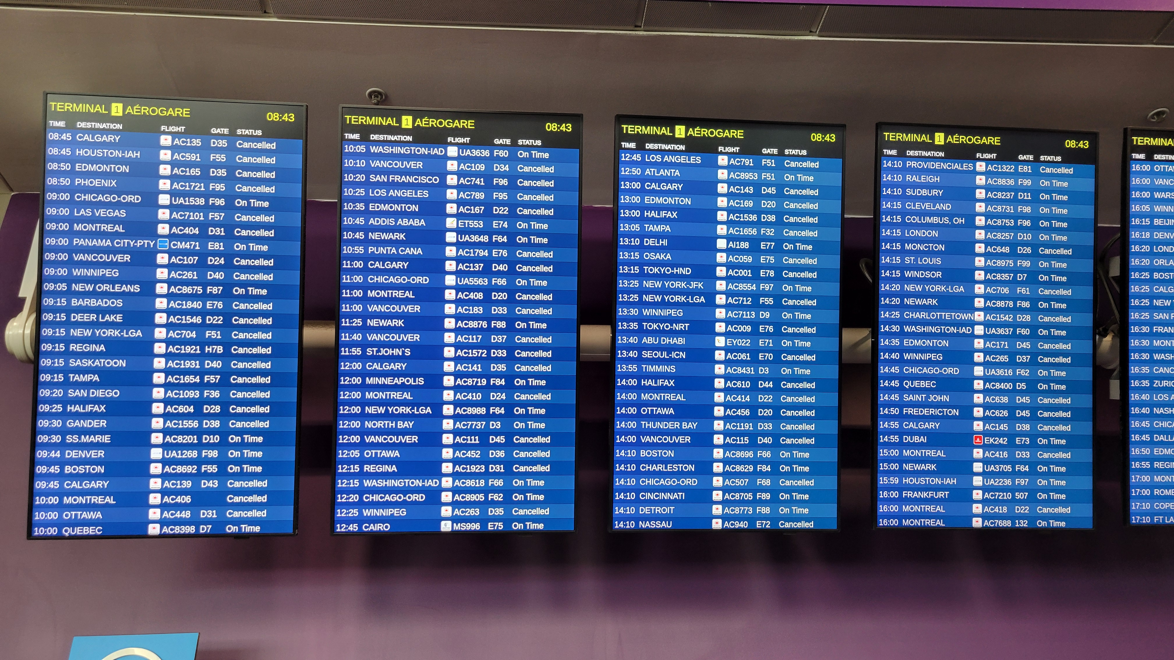 Airport departure boards showing mass flight cancellations in red, Air Canada strike at Toronto Pearson International Airport 2025