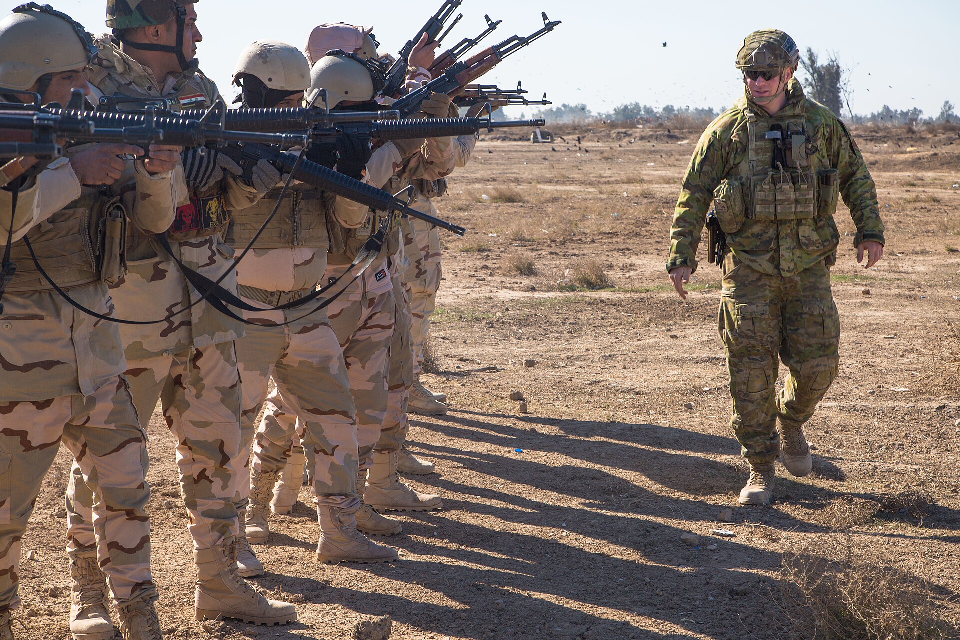 A coalition trainer supervises local security force recruits during weapons training at a Middle East military camp