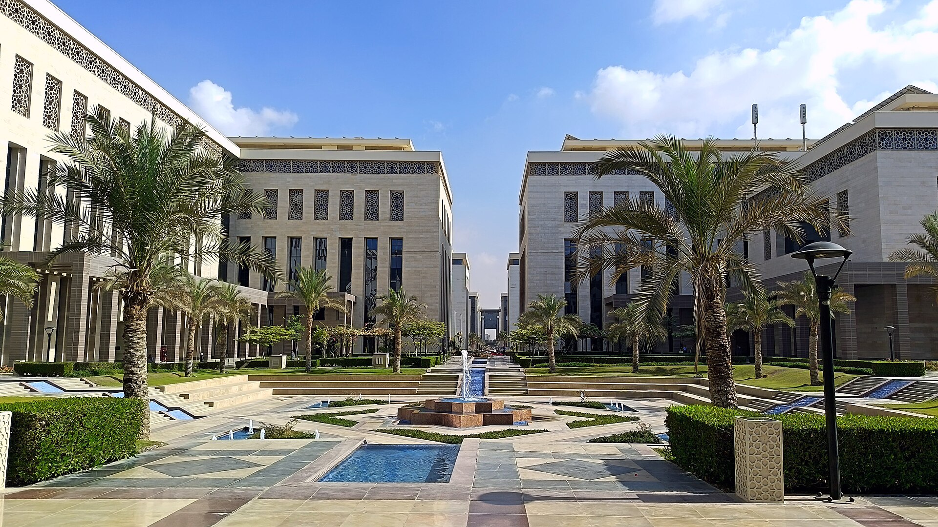 Egypt New Administrative Capital government district — modern limestone buildings with central plaza and palm trees