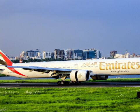 Emirates Boeing 777-300ER on runway, with Emirates livery and gold script markings visible on fuselage
