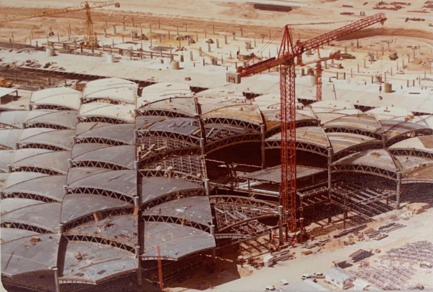 Aerial view of King Khalid International Airport main terminal under construction mid-1970s showing the distinctive Teflon-coated fiberglass tent-module roof design