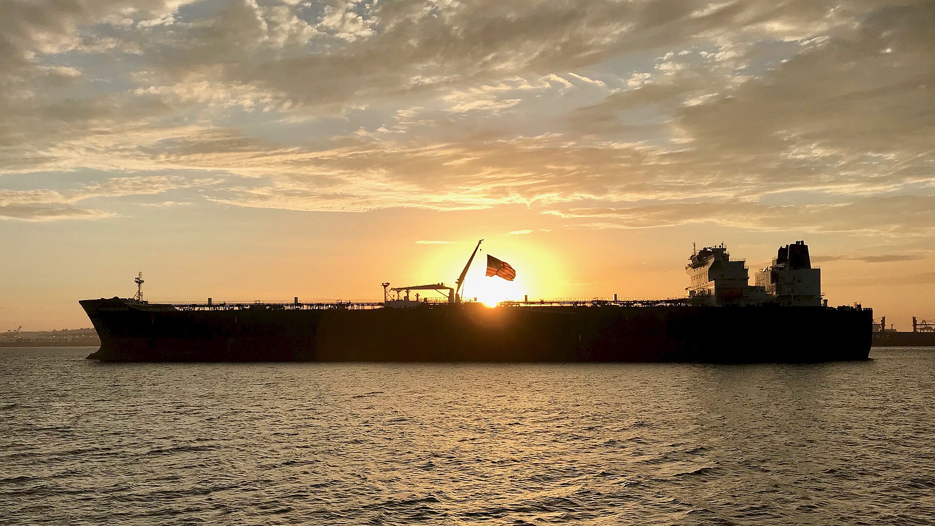 Oil tanker silhouetted against a sunset sky at anchor, Long Beach harbor