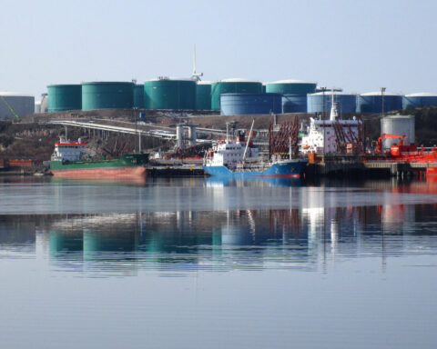 Oil tankers loading at a petroleum refinery terminal with large storage tanks in the background, Preemraff Lysekil, Sweden