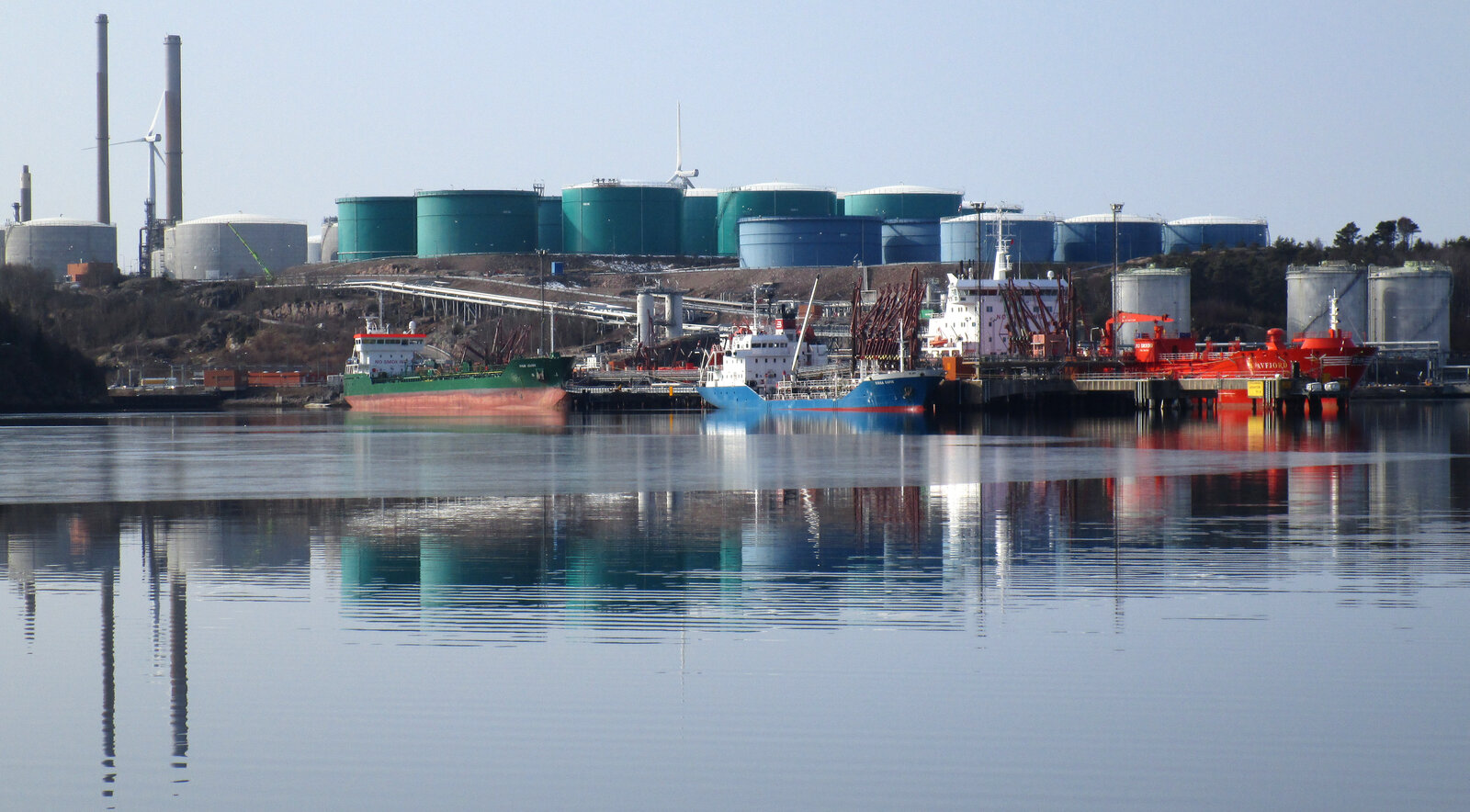 Oil tankers loading at a petroleum refinery terminal with large storage tanks in the background, Preemraff Lysekil, Sweden