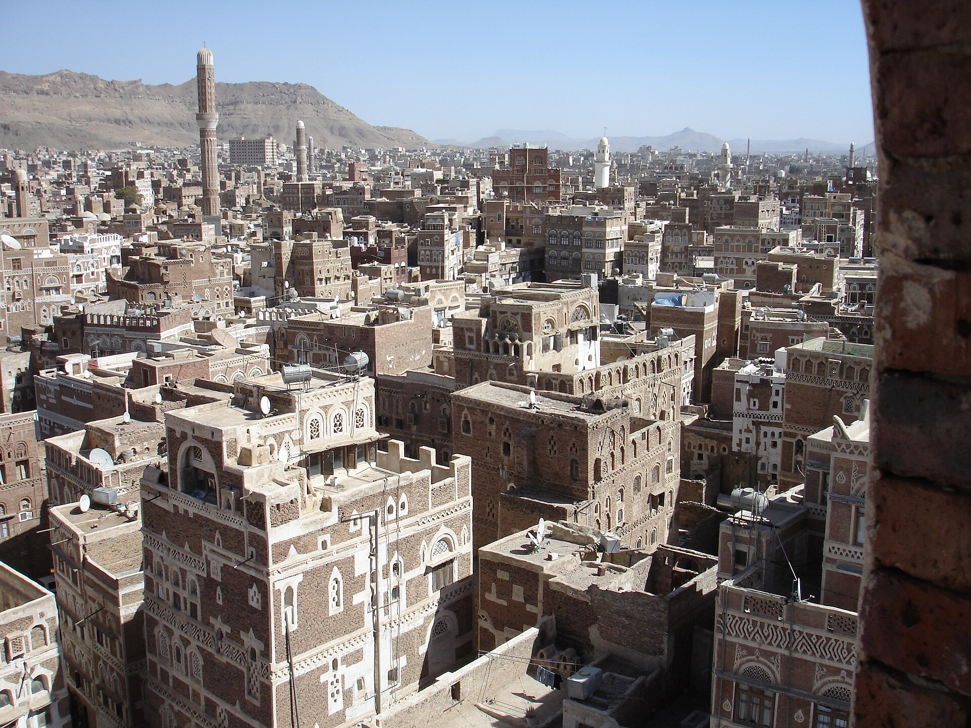 Panoramic view of Old Sana'a, a UNESCO World Heritage Site, showing dense traditional tower-house architecture and minarets