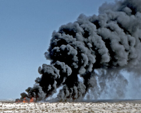 Oil waste burn-off at Saudi Aramco Ras Tanura facility, 1959 — black smoke column over the Saudi desert