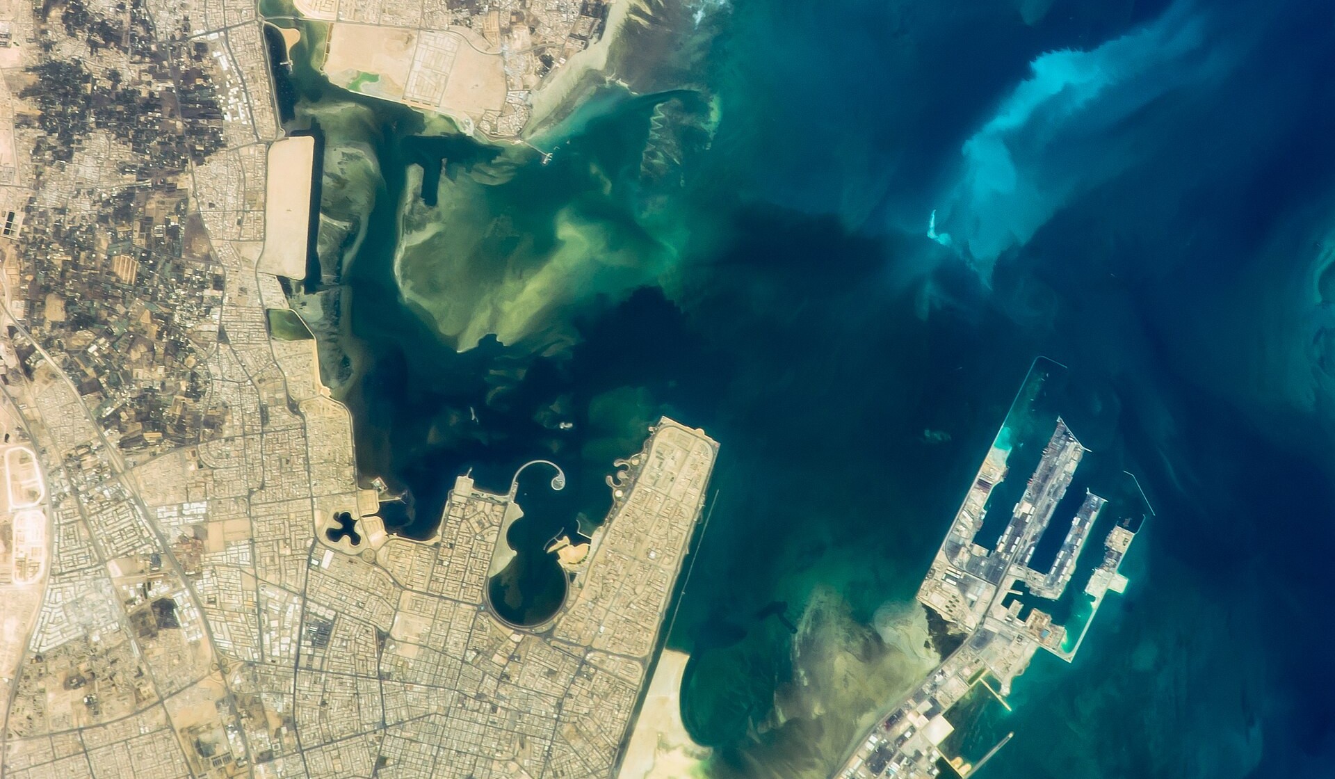 Ras Tanura crude oil export terminal and Aramco company town on the Saudi Arabian Gulf coast, photographed from the International Space Station by the Expedition 34 crew — the pier and loading berths for supertankers are visible in the lower right