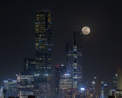 Riyadh King Abdullah Financial District skyline at night with full moon rising between KAFD towers