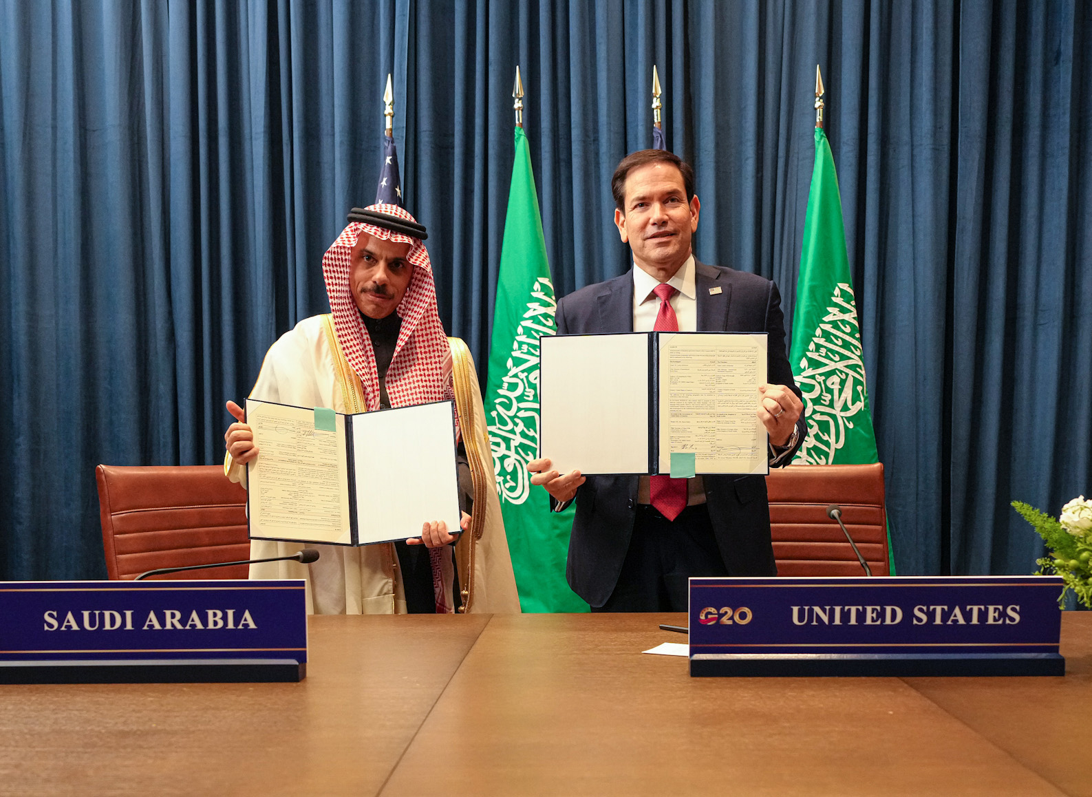 Secretary of State Marco Rubio and Saudi Foreign Minister Prince Faisal bin Farhan hold signed documents at G20 foreign ministers meeting in Atlanta