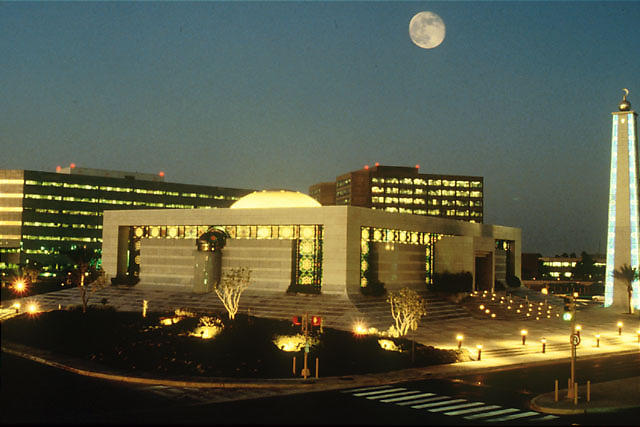 Saudi Aramco headquarters compound in Dhahran at night, showing the Al Mujamma mosque, administration building, and the company obelisk — the institutional seat of the world's largest oil company