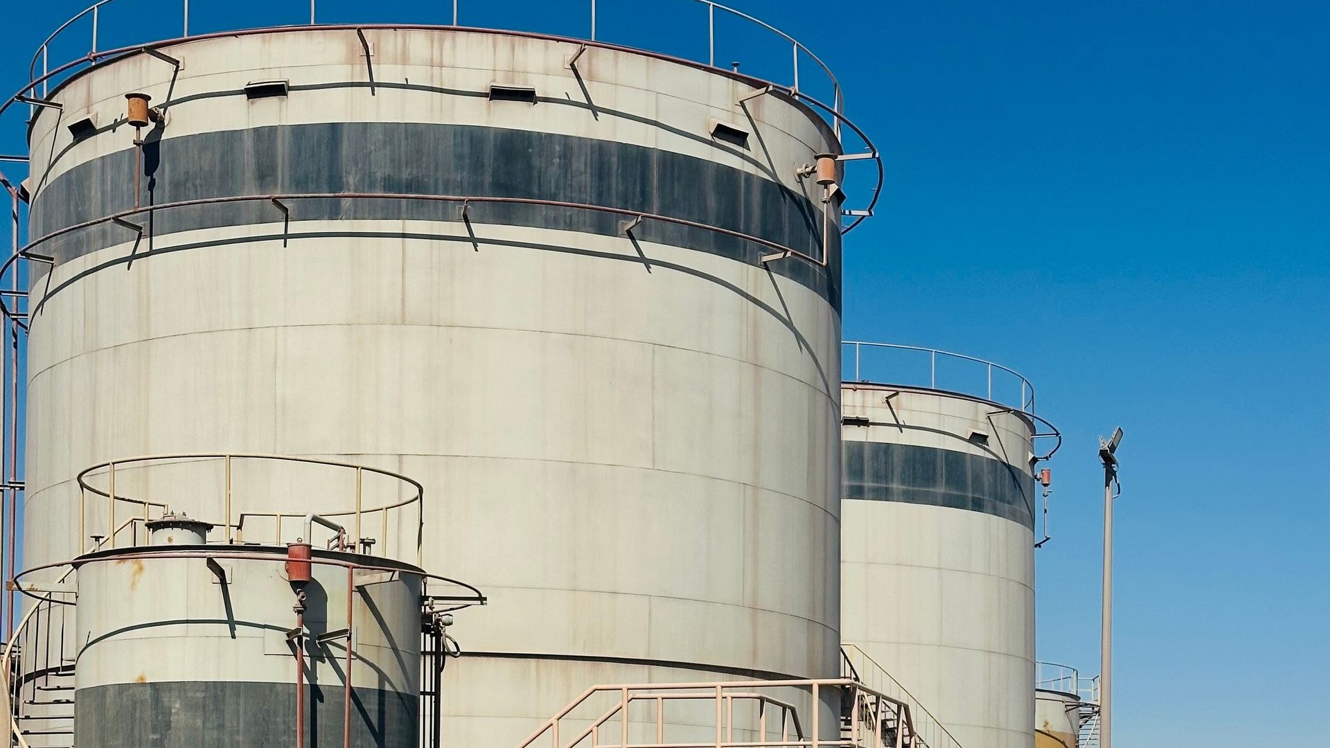 Oil storage tanks at a Saudi Arabia energy facility under a clear desert sky — the Eastern Province houses the bulk of Aramco's onshore and offshore production infrastructure