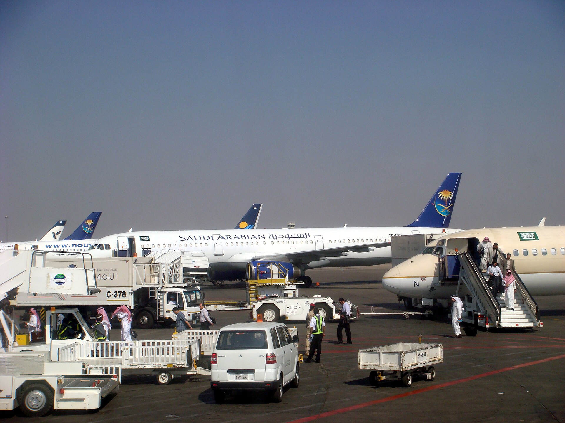 Saudi Arabian Airlines Saudia aircraft on apron at Saudi airport with ground crew and passengers