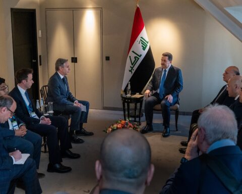 Iraqi Prime Minister Mohammed Al-Sudani meets with foreign officials, Iraqi flag in background, Munich 2023