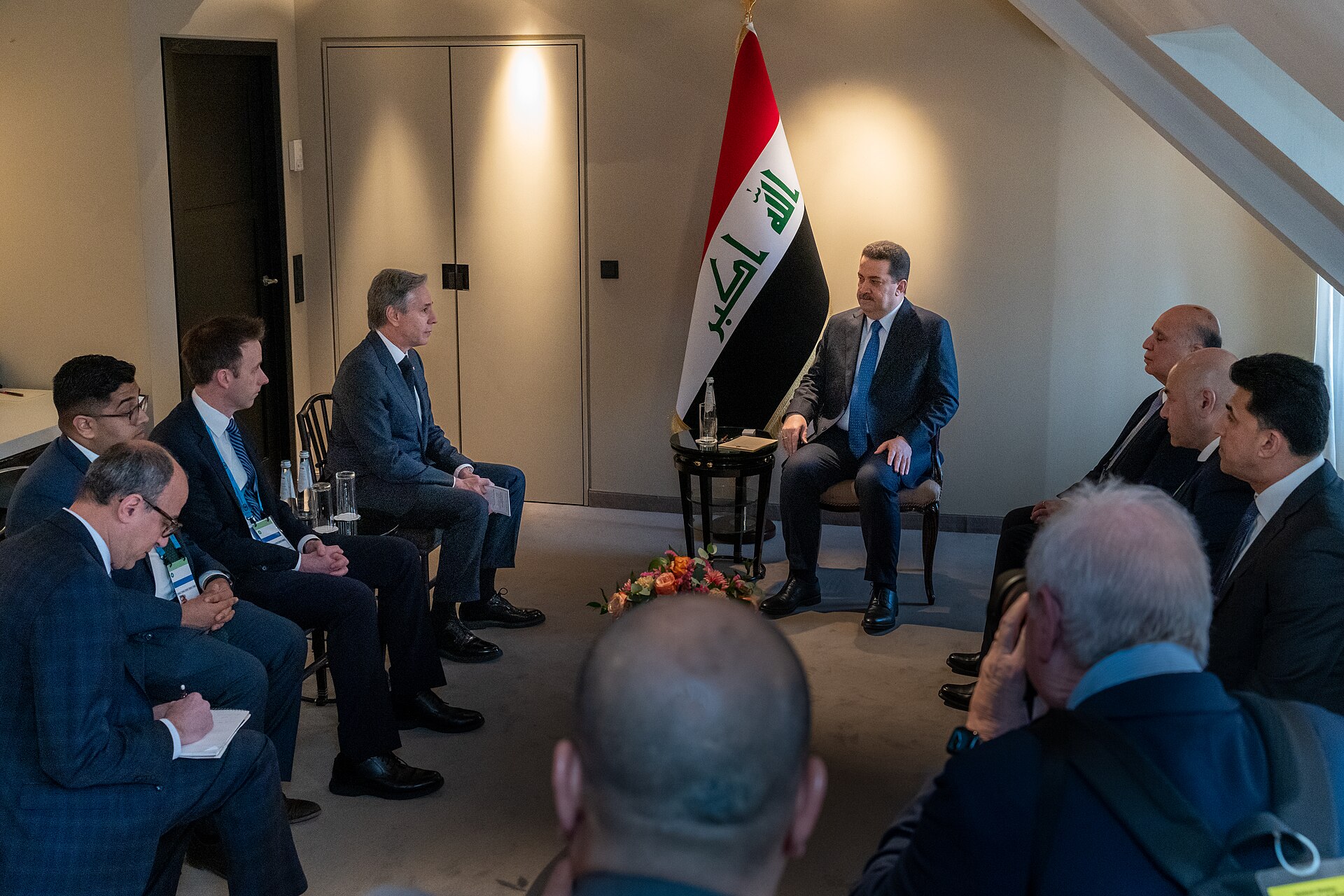 Iraqi Prime Minister Mohammed Al-Sudani meets with foreign officials, Iraqi flag in background, Munich 2023