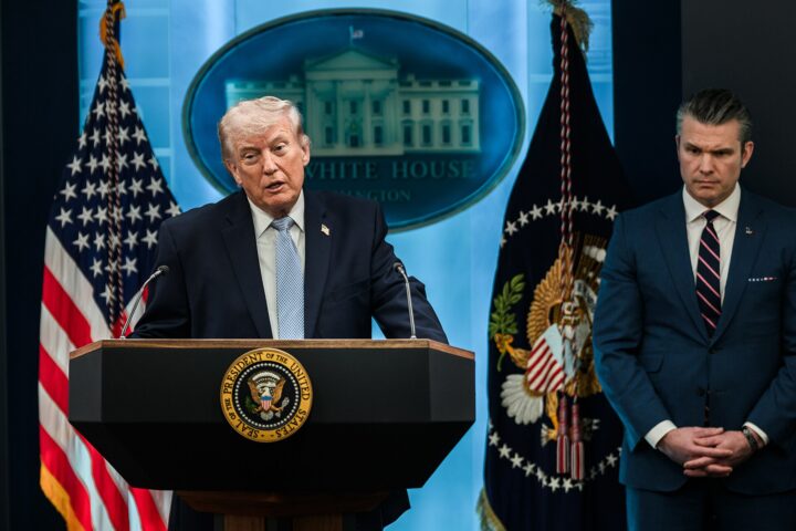 President Trump speaks at White House podium alongside Defense Secretary Hegseth during media briefing on Iran operations, April 2026