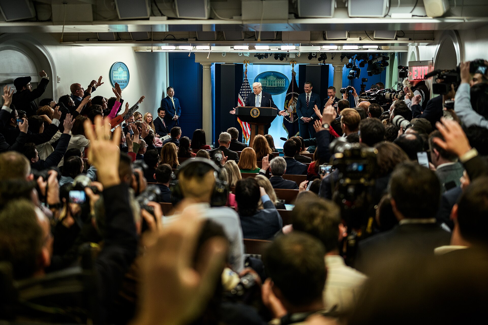 Trump addresses packed White House press briefing room on Iran, with journalists raising hands for questions, April 2026