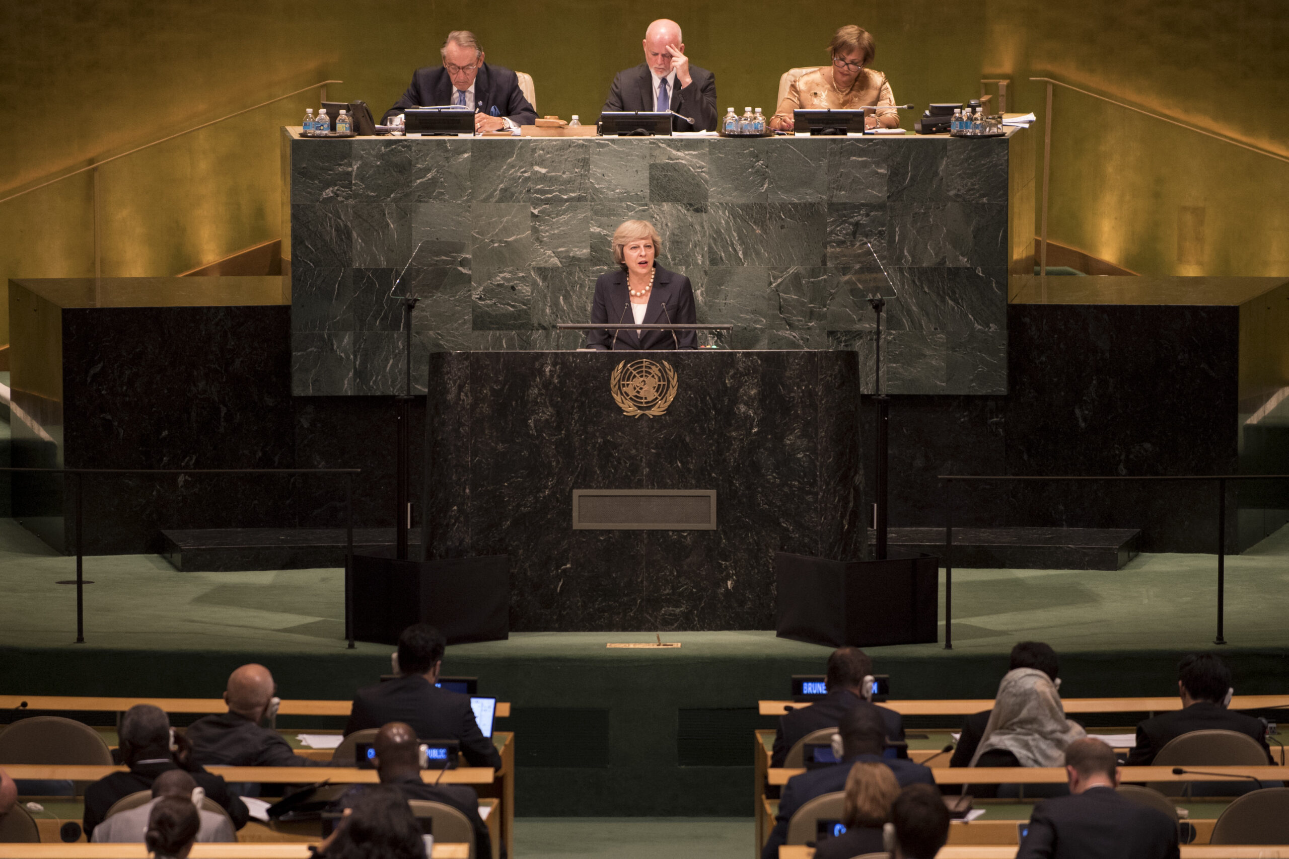 The UN General Assembly Hall during a high-level plenary session, with delegates at their seats and a speaker at the podium beneath the UN emblem