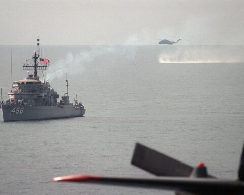 USS Inflict MSO-456 ocean minesweeper at anchor in the Persian Gulf with RH-53D Sea Stallion helicopter conducting minesweeping operations, 1987