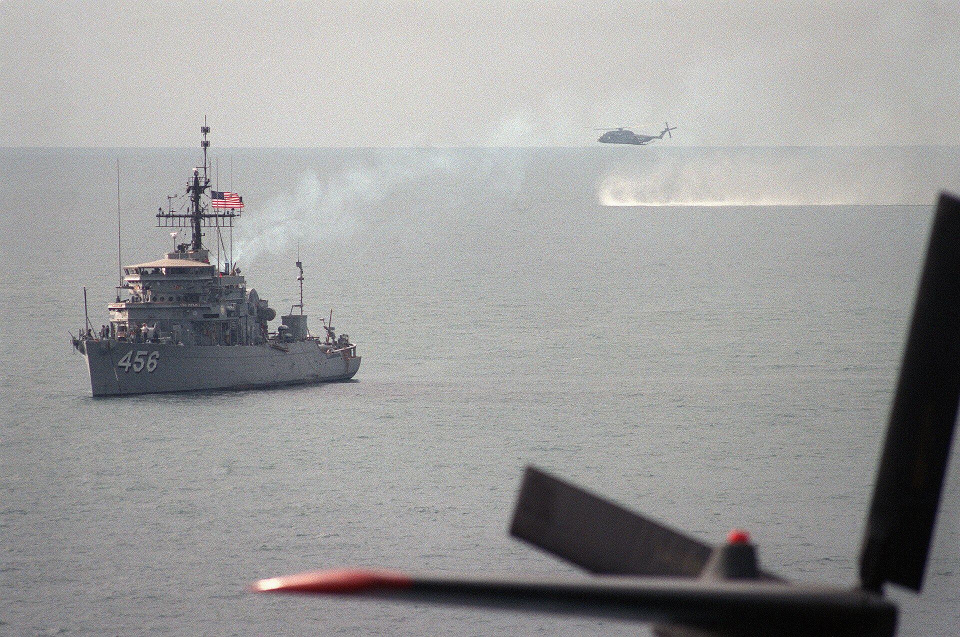 USS Inflict MSO-456 ocean minesweeper at anchor in the Persian Gulf with RH-53D Sea Stallion helicopter conducting minesweeping operations, 1987