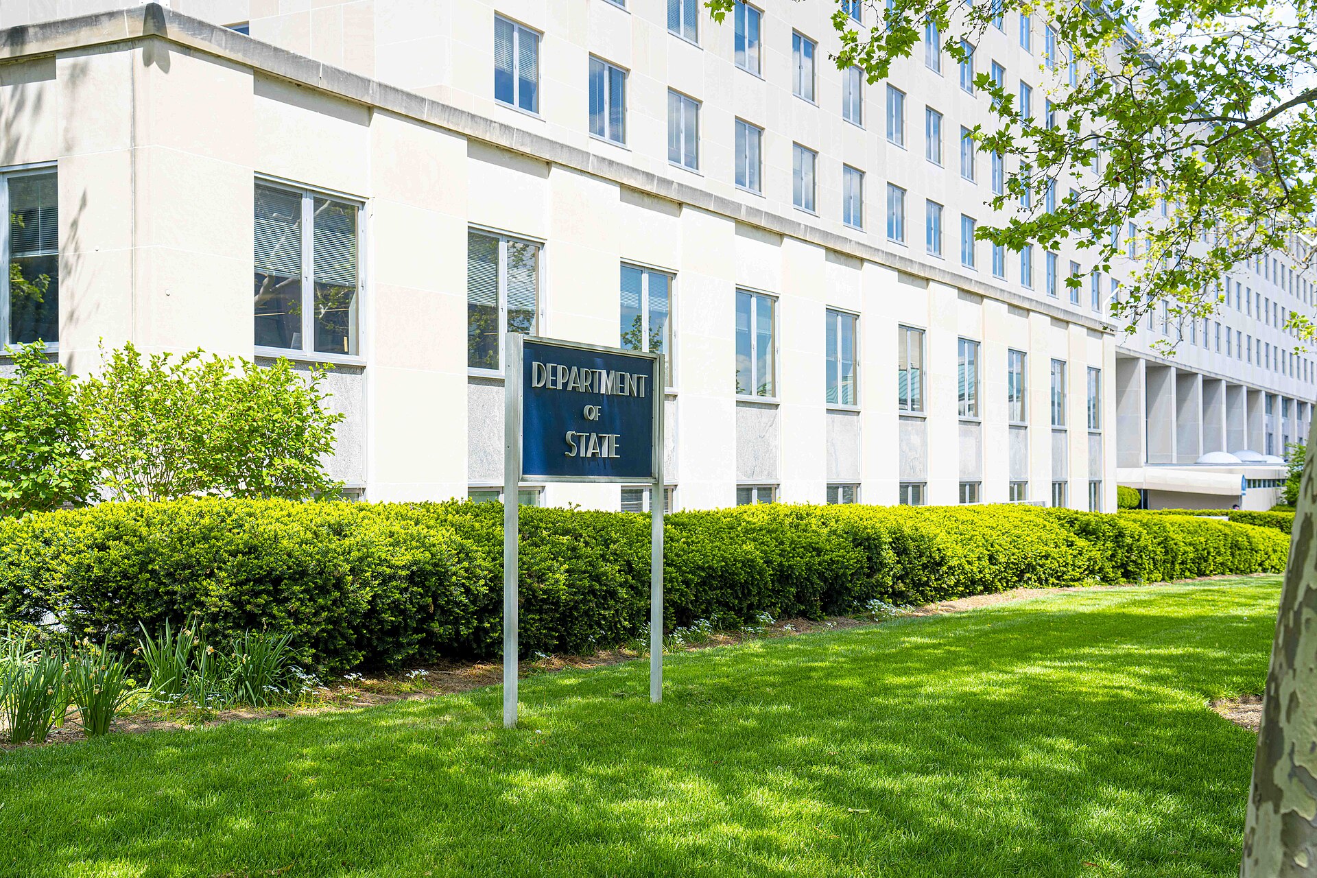 Exterior of the US Department of State Harry S Truman Building in Washington DC with the Department of State sign visible on the lawn