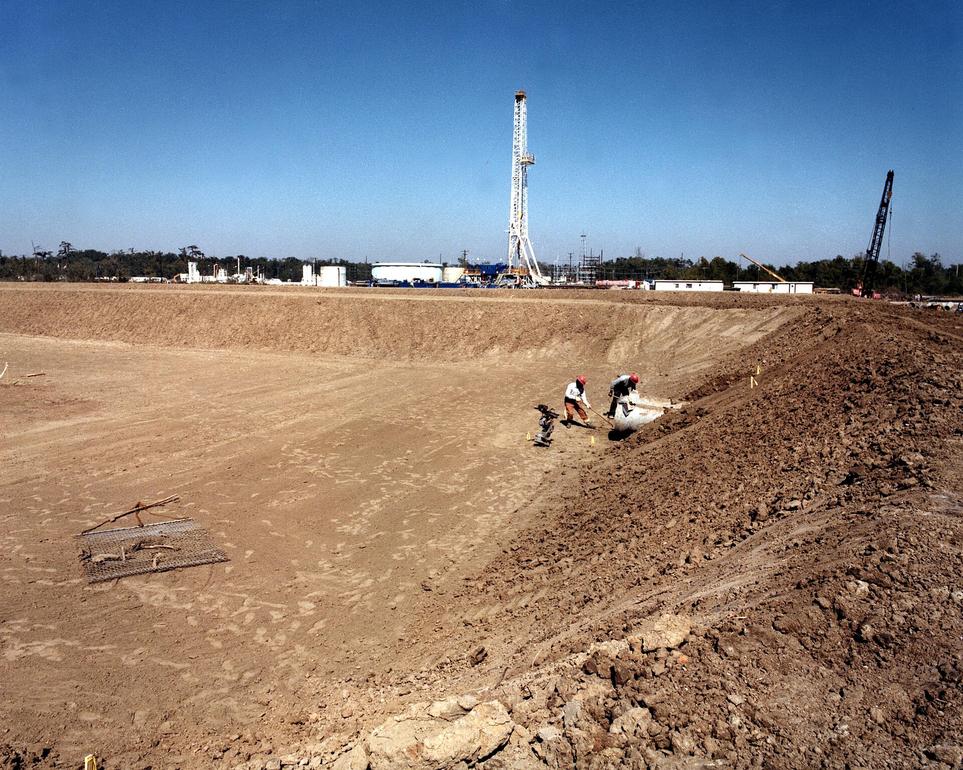 Brine reservoir south of Cavern 15 at the US Strategic Petroleum Reserve salt dome facility, with drilling rig in background