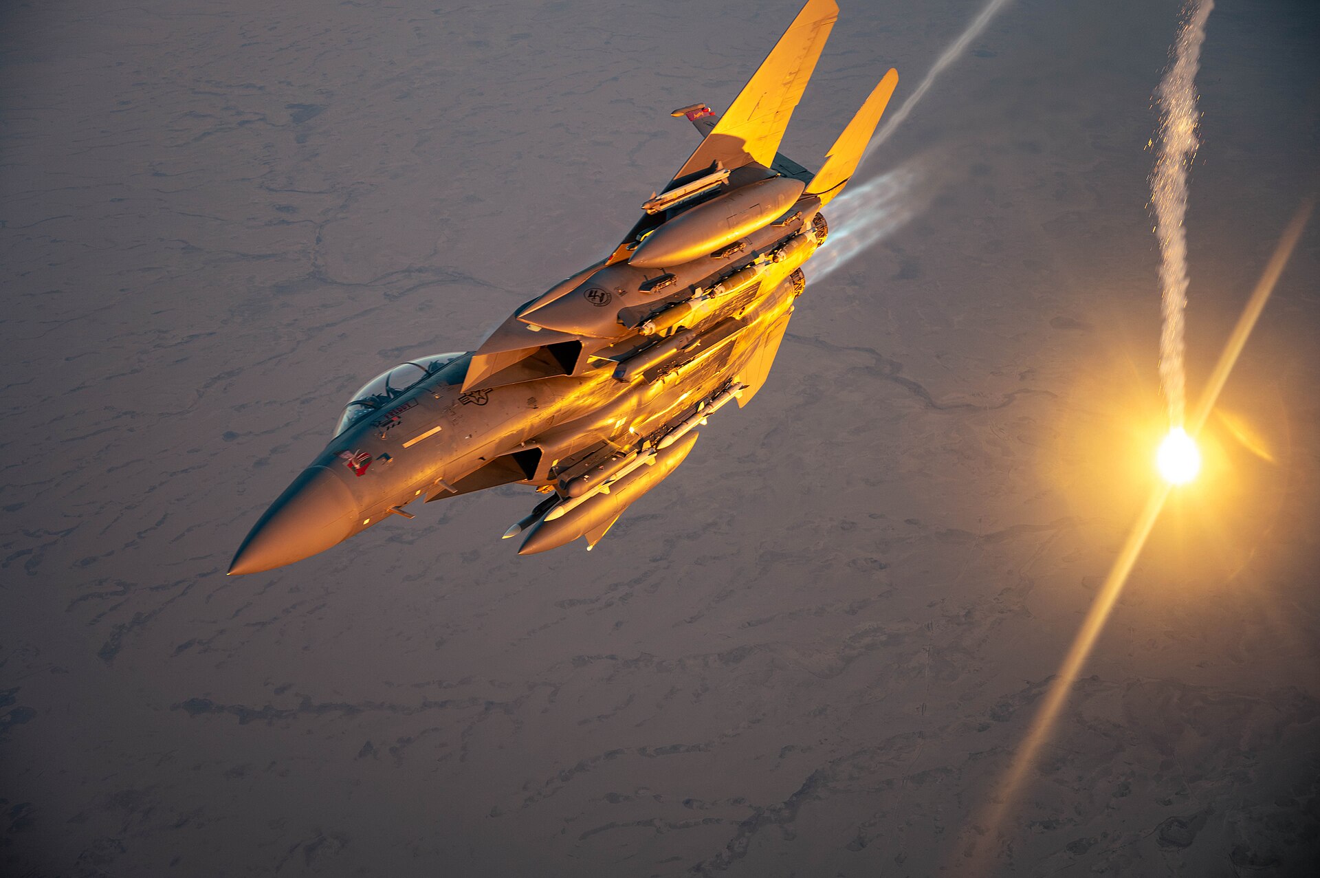 USAF F-15E Strike Eagle performs a flare check while on combat patrol over desert terrain, March 2025