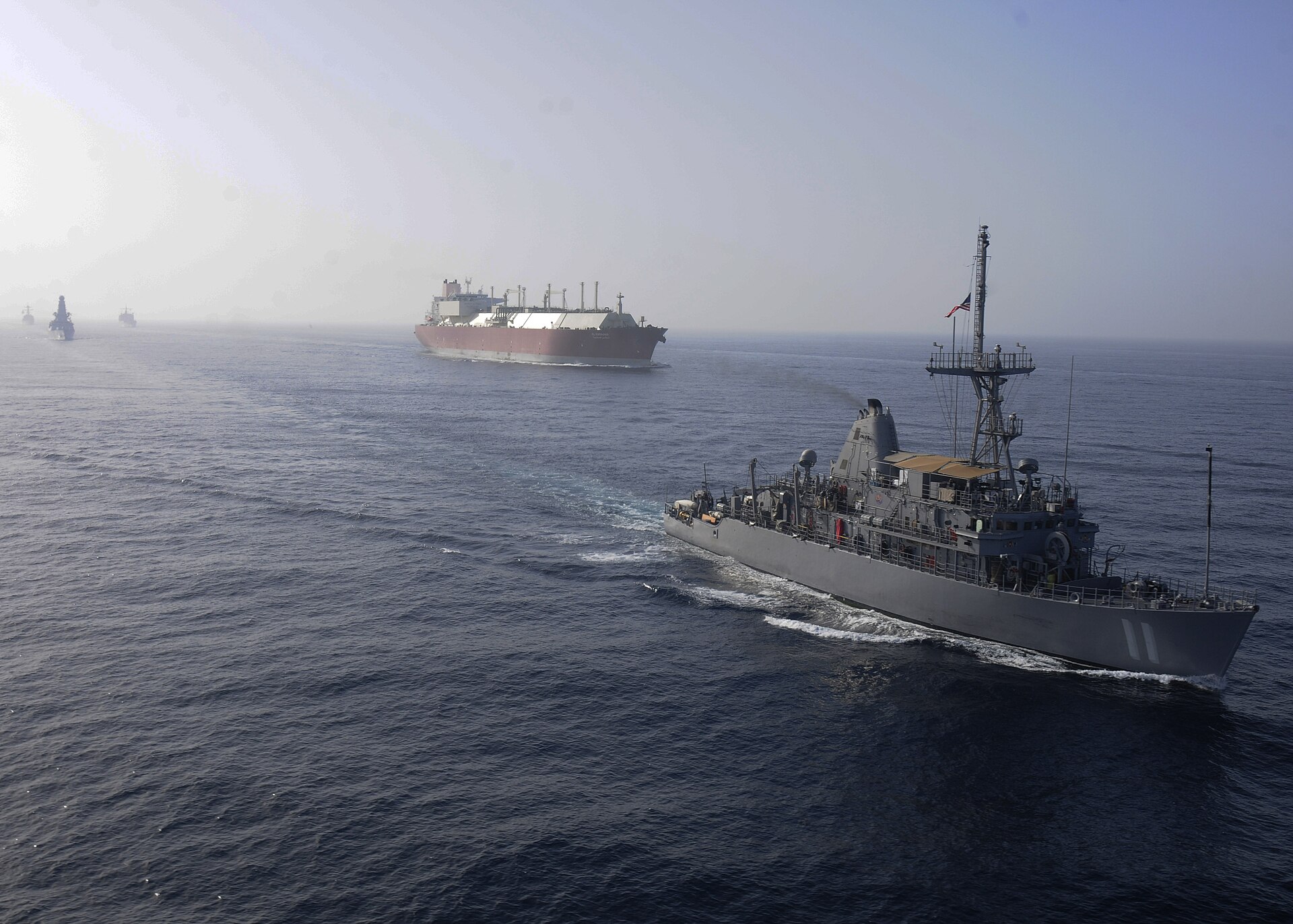 The mine countermeasures ship USS Gladiator (MCM-11) conducts convoy escort operations with a large natural gas tanker during International Mine Countermeasures Exercise (IMCMEX) 2013 in the Persian Gulf, demonstrating the naval mine-clearance operations CENTCOM has deployed to keep Hormuz shipping lanes open