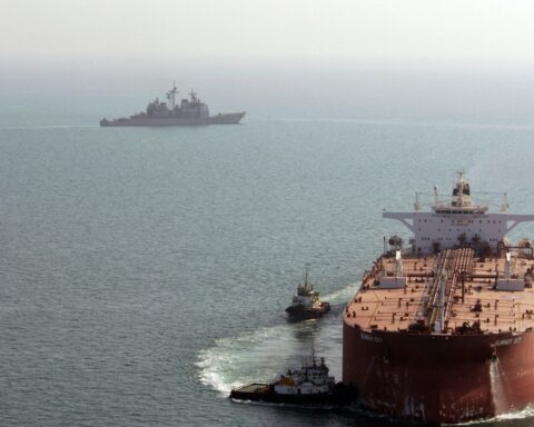 USS Mobile Bay (CG-53) guided missile cruiser patrols the Persian Gulf as the supertanker Summer Sky is guided into position at Iraq's Al Basrah Oil Terminal — the type of crude-oil loading infrastructure whose exports depend on open access through the Strait of Hormuz